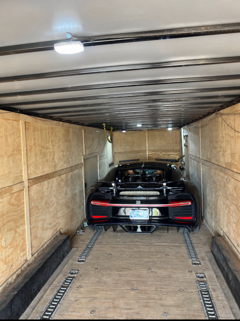 Black Bugatti inside an enclosed vehicle transport trailer