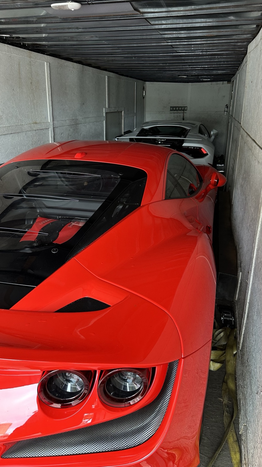 Red Ferrari and silver Lamborghini inside an enclosed trailer